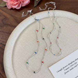 Detail of silver snake chains with colorful beads on a tray showing texture and link quality