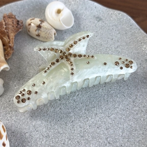 Détail de la pince à cheveux marbrée avec étoile de mer en strass et coquillages