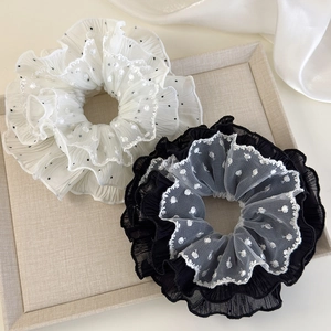 Close-up of elegant lace-edged organza hair scrunchie with polka dots and floral patterns