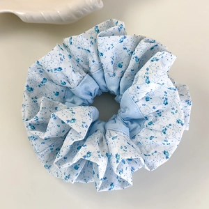 Détail d'un chouchou à imprimé floral bleu clair avec texture de tissu froissé