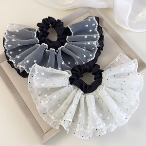 Detail of lace mesh scrunchie featuring elegant polka dot embroidery and wavy edges