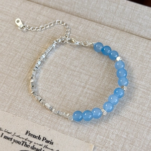 Détail du bracelet en perles de verre bleues avec étiquette argent 925 sur textile
