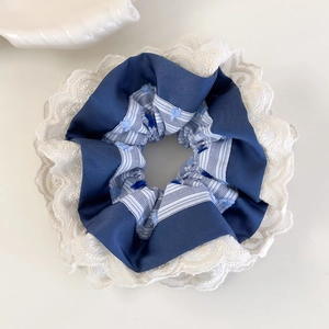 Détail du chouchou à carreaux bleus avec dentelle et pompons doux pour la coiffure