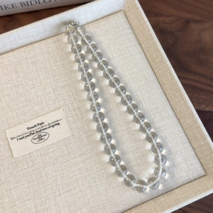 Detail of high-transparency round acrylic glass beads necklace with silver metal clasp