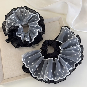 Detail of elegant black and white layered lace hair tie with polka dots on a display tray