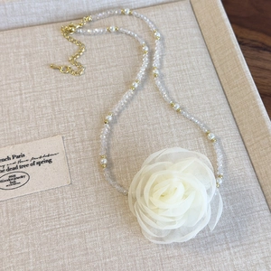 Detail of beaded choker necklace featuring a large cream rose flower and golden clasp