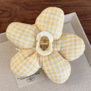 Détail de la pince à cheveux fleur en coton vichy jaune sur plateau texturé
