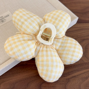 Détail d'une pince à cheveux fleurie en tissu vichy jaune et centre en résine crème