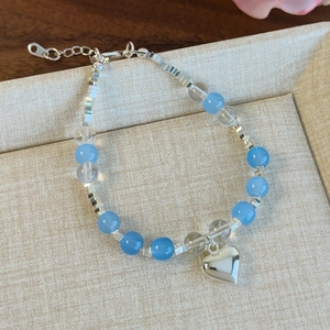 Détail d'un bracelet de perles bleues avec un pendentif en forme de cœur argenté