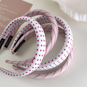 Pink striped and polka dot sponge headbands with handmade label on minimalist background