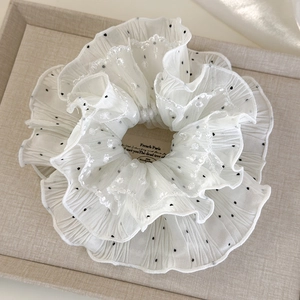 Detailed view of white polka dot scrunchie with delicate lace edges and soft chiffon folds