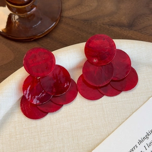 Gros plan de boucles d'oreilles en nacre rouge avec des sequins ronds en cascade