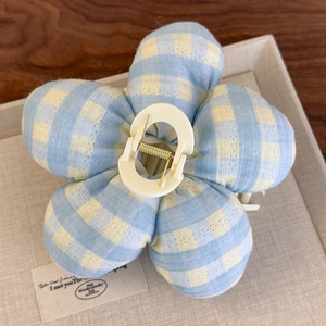 Vue détaillée d'une pince à cheveux en forme de fleur en tissu à carreaux bleus et jaunes