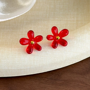 Gros plan de boucles d'oreilles fleurs rouges avec un petit détail de perle dorée au centre