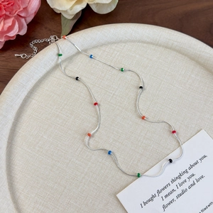 Detailed view of silver snake chain necklace with vibrant multi-colored beads on a tray