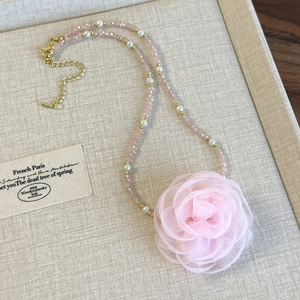 Close-up of pink mesh rose necklace with delicate pearlescent beads and gold lobster clasp