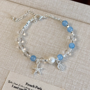 Détail de breloques étoile de mer et coquillage sur bracelet perles bleu et argenté