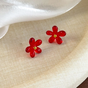 Vue macro détaillée de boucles d'oreilles fleurs rouges translucides avec perle dorée centrale