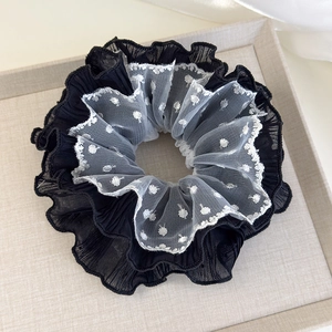 Detailed close-up of layered black chiffon and white lace polka dot scrunchie hair accessory