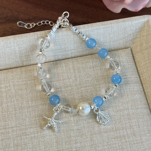 Détail du bracelet en perles avec perles de verre bleues et breloques étoile de mer