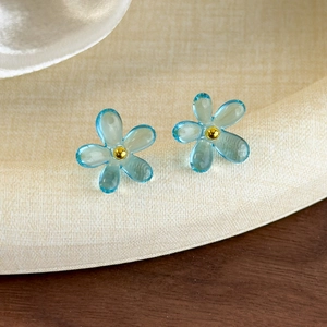 Vue macro de boucles d'oreilles fleurs bleues translucides avec centres dorés stylés