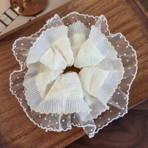 Detailed close-up of ivory lace scrunchie with polka dot mesh on a vintage wooden tray