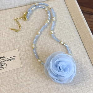 Close-up of handmade beaded choker featuring a light blue mesh rose and pearl accents