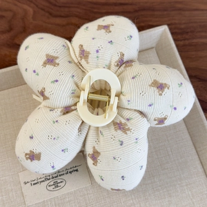 Détail d'une pince à cheveux fleurie en tissu tricoté avec ours et motifs floraux