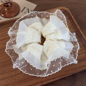 Detailed view of beige lace scrunchie with layered polka dot mesh on wooden tray