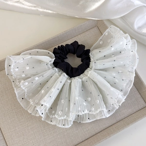 Detail of white lace hair scrunchie with black polka dots and heart patterns