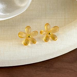 Détail de boucles d'oreilles fleurs ambre translucides avec perles dorées centrales