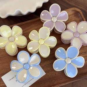 Pinces à cheveux en forme de fleur pastel présentées sur un plateau en bois
