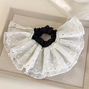 Detail of elegant black and white polka dot lace scrunchie on a soft fabric tray