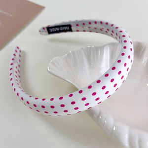 Detail of handmade cream headband with pink polka dots and black handmade label