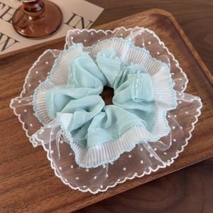 Detailed texture of mint green lace scrunchie with white polka dots and pleated edges
