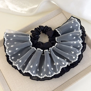Detail of black satin scrunchie with layered white lace polka dot ruffle edge