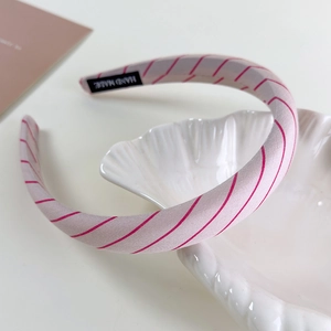 Detailed macro view of handmade light pink striped headband on shell tray with logo