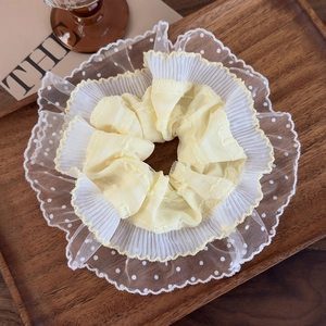 Detail of light yellow lace hair scrunchie with white polka dots on wooden tray