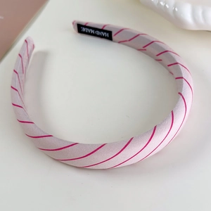 Detail of pink striped sponge headband showing fabric texture and handmade label