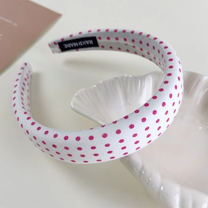 Macro shot of sweet pink polka dot headband showing a handmade label on fabric