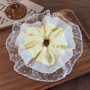 Detailed shot of yellow pleated fabric hair scrunchie with white polka dot lace trim