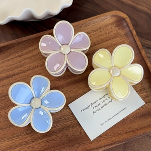 Vue détaillée de trois pinces à cheveux fleurs brillantes en violet, jaune et bleu