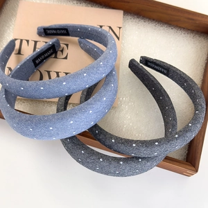 Padded denim rhinestone headbands in light blue and dark grey on a wooden tray