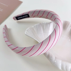 Detail of pink striped sponge headband with 'HAND MADE' label on a shell tray
