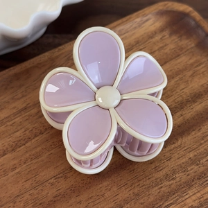 Détail de la pince à cheveux en forme de fleur lavande et crème sur support en bois