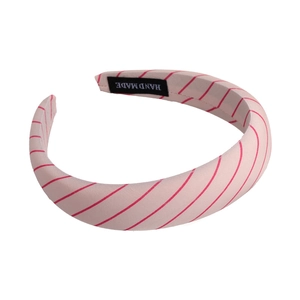 Macro detail of a pink sponge headband featuring red diagonal stripes and handmade label