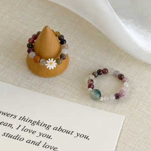 Handmade daisy beaded rings with natural stones on a minimalist aesthetic display