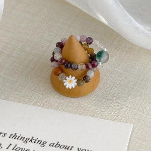 Daisy colorful beaded ring set featuring natural stones on a wooden display stand