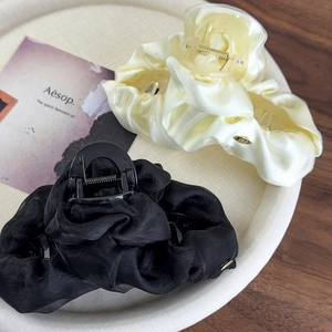 Detail of luxury pleated chiffon hair claws in cream yellow and black with gold accents