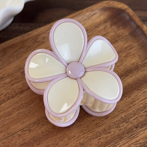 Vue détaillée d'une jolie pince à cheveux fleurie crème et rose sur un plateau en bois